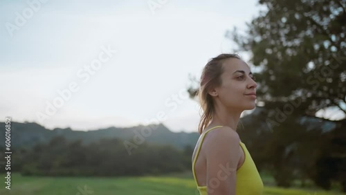 slow motion portrait of Young Athlete Woman enjoyinng beautiful green rural field landscape after running outdoors along Green Fields. photo