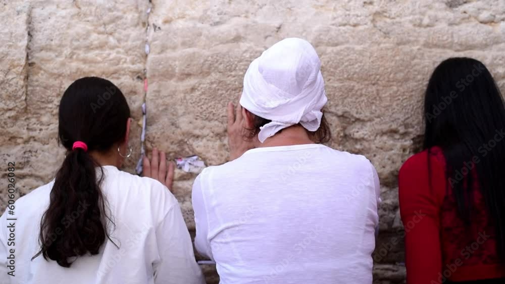 Three women standing and praying on Western Wall with notes of paper containing written prayers placing in cracks and crevices. Wall old part of Jerusalem city. tourism, travel and vacation to Israel Three women standing and praying on Western Wall with notes of paper containing written prayers placing in cracks and crevices. Wall old part of Jerusalem city. tourism, travel and vacation to Israel