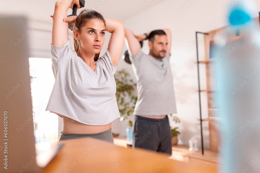 Fototapeta premium Couple doing tricep workout using dumbbells