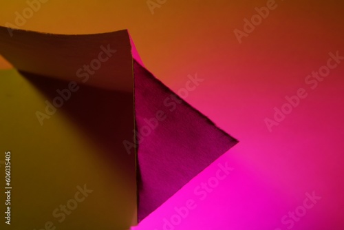 La figura de papel doblado forma un triángulo con luz amarilla y magenta con líneas rectas y sombra, formando un diseño abstracto y rústico muy original y bonito para fondos