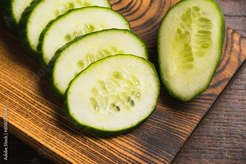 Flatlay, sliced cucumber on a dark wooden board in rustic style, cucumber slices close-up