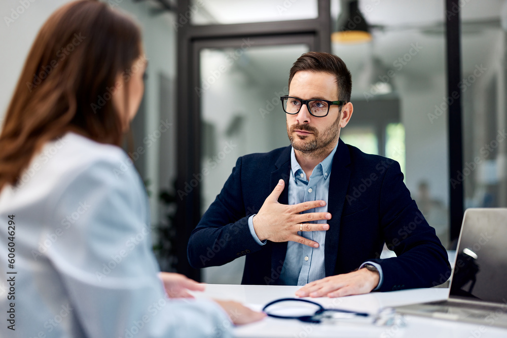 A man touches his chest and complains of very strong pain to a female doctor. A man touches his chest and complains of very strong pain to a female doctor.