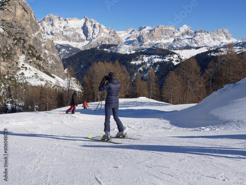 Alpine Skiers Descending a Beautiful Snowy Slope and a view of the Beautiful Surrounding Landscape of the Snow-covered of the Italian alps Dolomites Mountains.