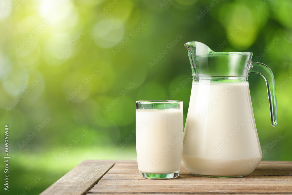 Glass and pitcher of fresh milk on wooden table with blur green garden background. Glass and pitcher of fresh milk on wooden table with blur green garden background.