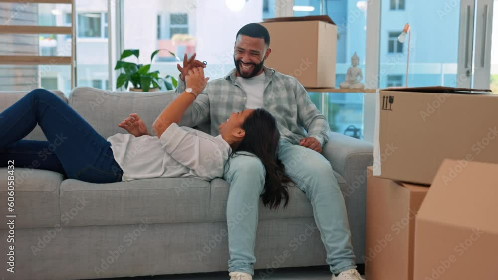 Happy couple, keys and relax on couch in new home with game, playing or bond with love for goal. Man, woman and happiness for young homeowner, achievement and comic with boxes, package or property Happy couple, keys and relax on couch in new home with game, playing or bond with love for goal. Man, woman and happiness for young homeowner, achievement and comic with boxes, package or property