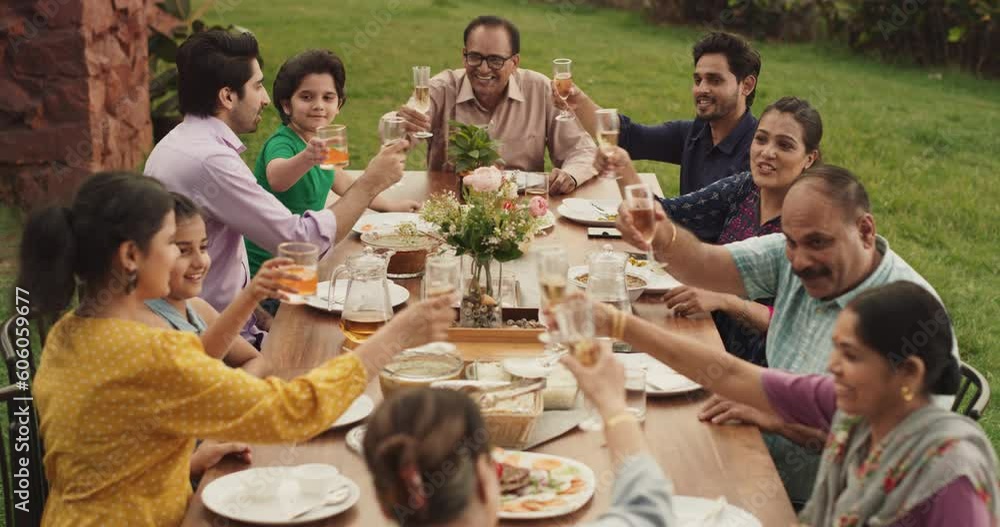 Close Up of Happy Indian Family Celebrating: Group of People Gathered Together at the Table Outdoors Raising their Glasses and Making a Toast. Big Family Garden Party Celebration and Festivities Close Up of Happy Indian Family Celebrating: Group of People Gathered Together at the Table Outdoors Raising their Glasses and Making a Toast. Big Family Garden Party Celebration and Festivities