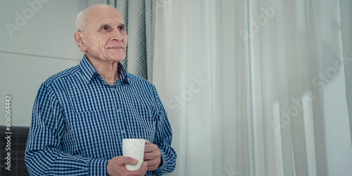 Portrait of old alone man with white coffee cup inside of room. Old people social isolation problem concept.