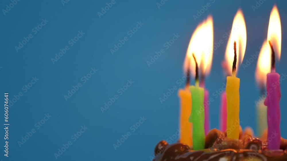 Lighted candles in a birthday cake rotation on a blue background. Candles in birthday cheesecake for home party.Copy space, Space for text Lighted candles in a birthday cake rotation on a blue background. Candles in birthday cheesecake for home party.Copy space, Space for text