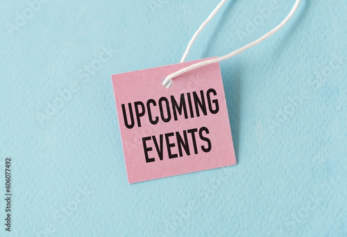 Upcoming Events Text on Pink Paper Card on Blue Background.