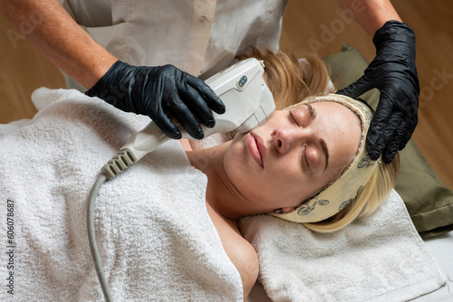 young woman on a stretcher performing an aesthetic treatment on the skin and face with the hifu technique performed by a beautician for body and health care photo