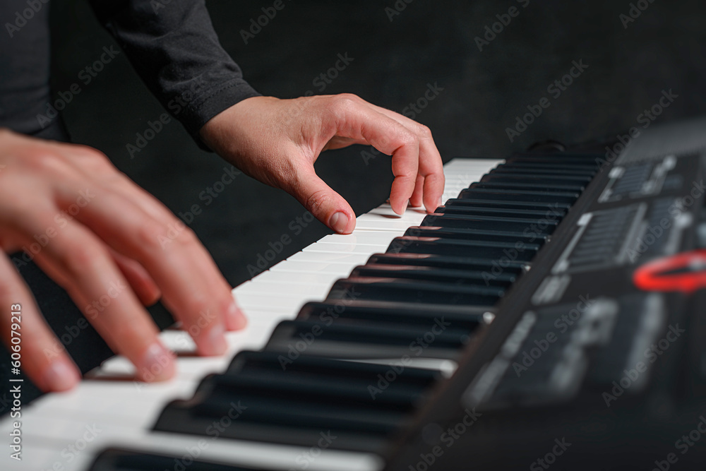 Fototapeta premium Playing a synthesizer on a dark background. The musician plays the synthesizer.