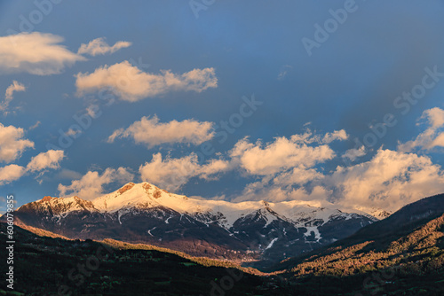 A scenics view of majestic snowy mountain summit  Les Orres  at golden hour  Hautes-alpes  France under a majestic blue sky and some white clouds