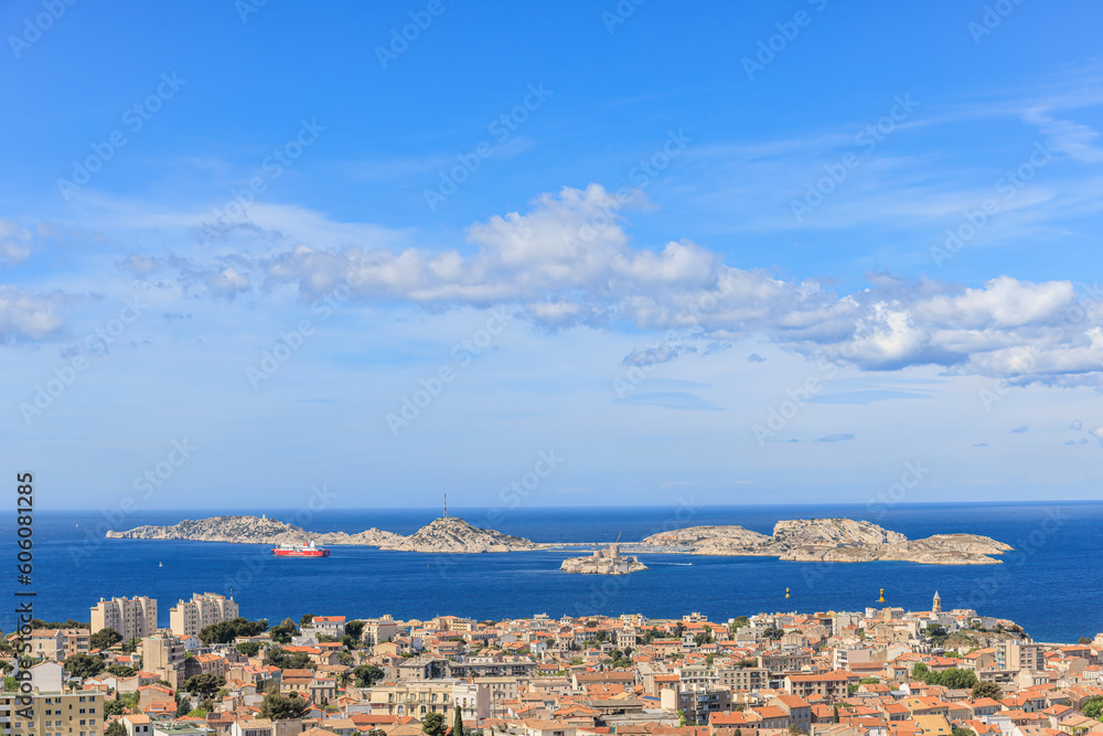 A scenics aerial view of the city of Marseille, bouches-du-rhône, France with a cruise ship and rocky island in the background at the port under a majestic blue sky and some white clouds