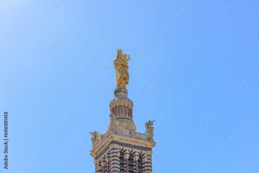 A scenics view of the Basilique Notre-Dame-de-la-Garde, la Bonne Mère gold statue, Marseille, bouches-du-rhône, France under a majestic blue sky A scenics view of the Basilique Notre-Dame-de-la-Garde, la Bonne Mère gold statue, Marseille, bouches-du-rhône, France under a majestic blue sky