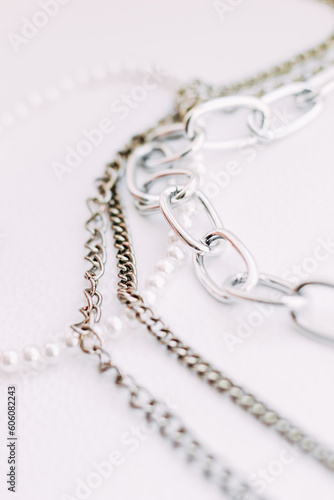 A necklace of white beads with chains of jewelry on a white aesthetic background.