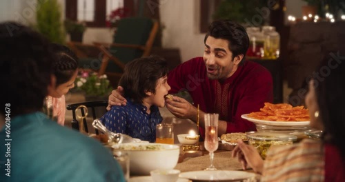 Family Time and Good Happy Memories: Indian Father Feeding his Son and Sharing Traditional Food on a Family Dinner. Family Bonding Memories Full of Love and Affection. Static Medium Shot photo