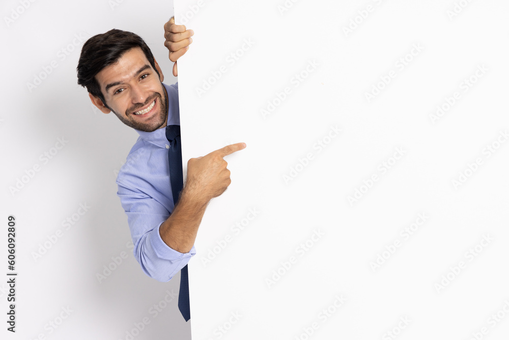 Young businessman pointing and standing behind the white blank banner or empty copy space advertisement board on white background, Looking at camera Young businessman pointing and standing behind the white blank banner or empty copy space advertisement board on white background, Looking at camera