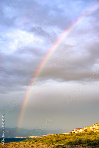 Vertical image of rustic coastline with rainbow and dark blue horizon © CarlosMSubirats