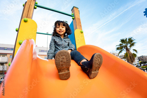 Foto A cute Dominican girl is playing on a swing in a playground