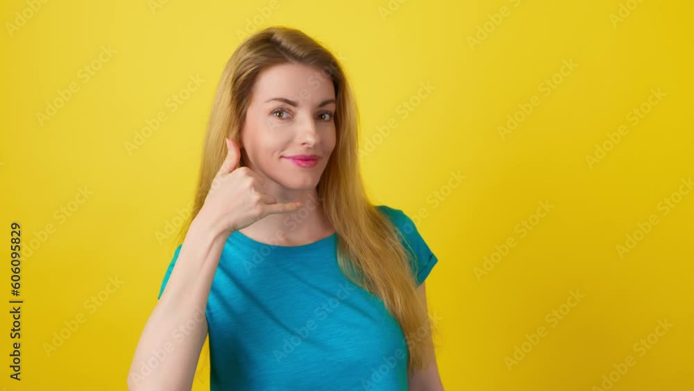 Wink and call me with happy woman face, making cellphone gesture, smiling flirty or playful. Young female lady eye blink with call sign for dating or fun in studio isolated on yellow background Wink and call me with happy woman face, making cellphone gesture, smiling flirty or playful. Young female lady eye blink with call sign for dating or fun in studio isolated on yellow background