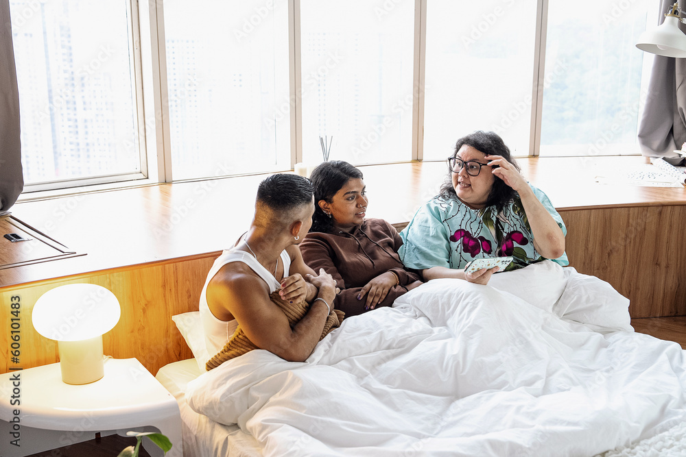 Obraz premium Three friends chatting and laughing together at home in bed