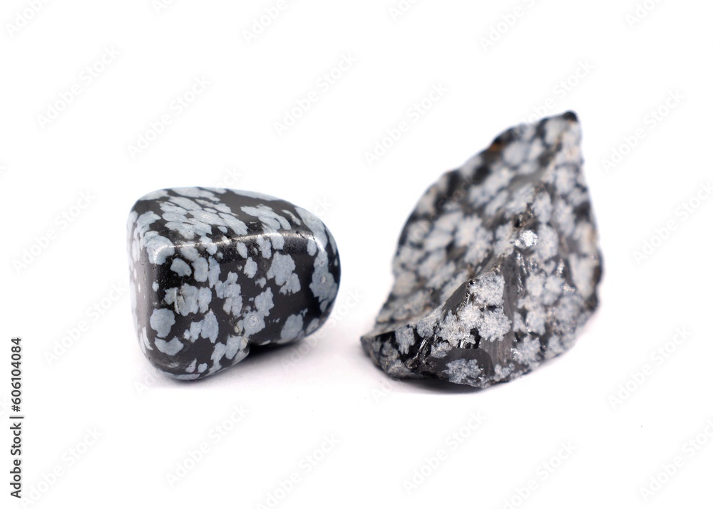 Two snowflake obsidian semi precious stones, one polished and one raw, on white background. Two snowflake obsidian semi precious stones, one polished and one raw, on white background.