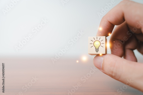 Hand holding creative light bulb icons on wood cube, analysis solution and development, Modern business, Innovative of new ideas.