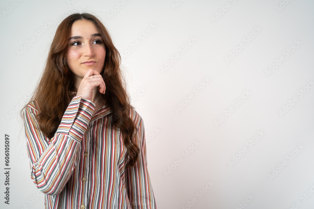 Young beautiful girl over isolated background with hand on chin thinking about question, pensive expression. Smiling with thoughtful face. Doubt concept. Young beautiful girl over isolated background with hand on chin thinking about question, pensive expression. Smiling with thoughtful face. Doubt concept.