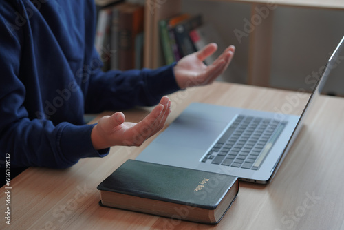 Religious man working on laptop at table.                               