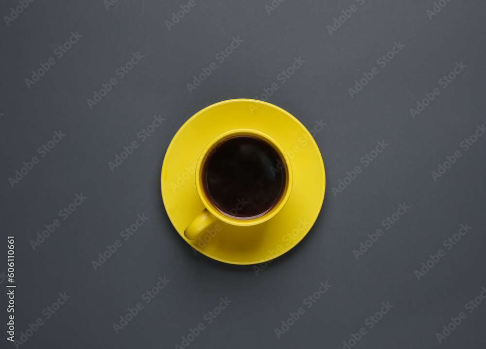Yellow ceramic cup with coffee on a saucer, dark gray background. Top view Yellow ceramic cup with coffee on a saucer, dark gray background. Top view