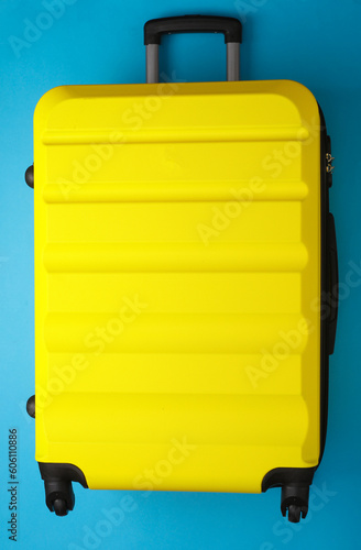 Yellow Wheeled suitcase, travel bag or luggage on blue background. Summer vacation, travel, trip concept. Top view