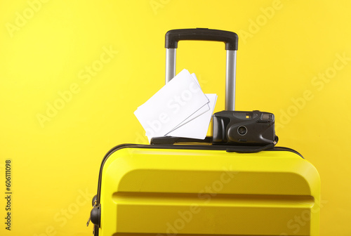 Yellow suitcase, travel bag or luggage with retro camera and blank photo mockups on yellow background. Summer vacation, travel, trip concept.