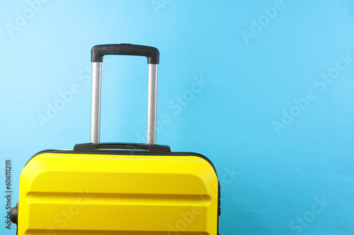 Yellow suitcase, travel bag or luggage on blue background. Summer vacation, travel, relocation concept.