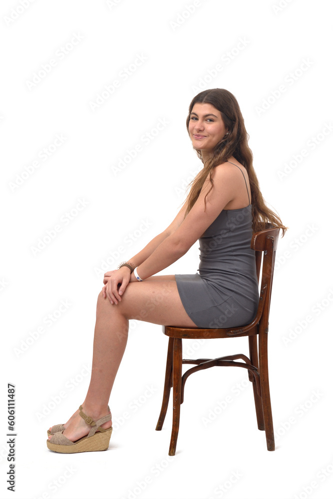side view of young girl sitting on chair happy and looking at camera on white background side view of young girl sitting on chair happy and looking at camera on white background