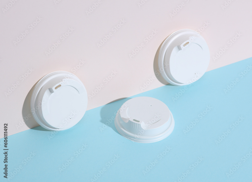White lids for hot drinks on a pastel background with shadow. Creative layout, minimalism White lids for hot drinks on a pastel background with shadow. Creative layout, minimalism