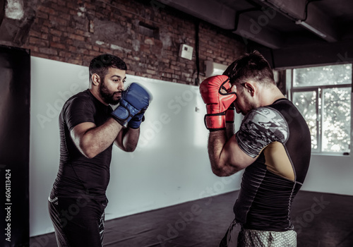 Two sparring partners of a kickboxer in boxing gloves practice kicks in a sports hall © splitov27