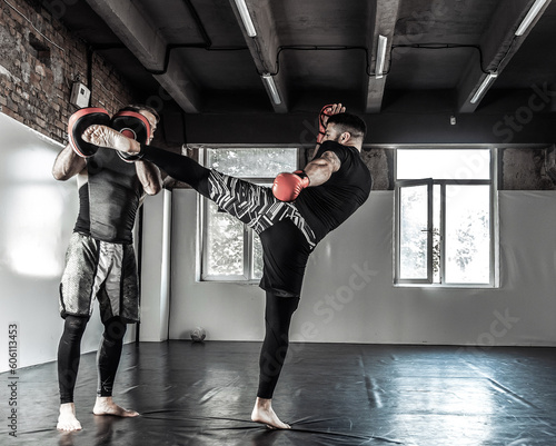 Male fighter training kicks with partner with training boxing paws © splitov27