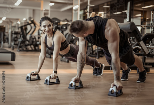 Fototapeta Naklejka Na Ścianę i Meble -  Workout together. Athletic man and woman are training doing push-ups in the gym. Healthy lifestyle