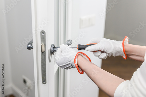 A man fixes a door with a screwdriver. Door lock repair