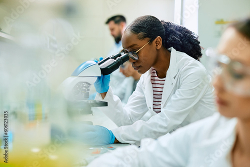 Black female scientist looking through microscope while working in laboratory Fototapet