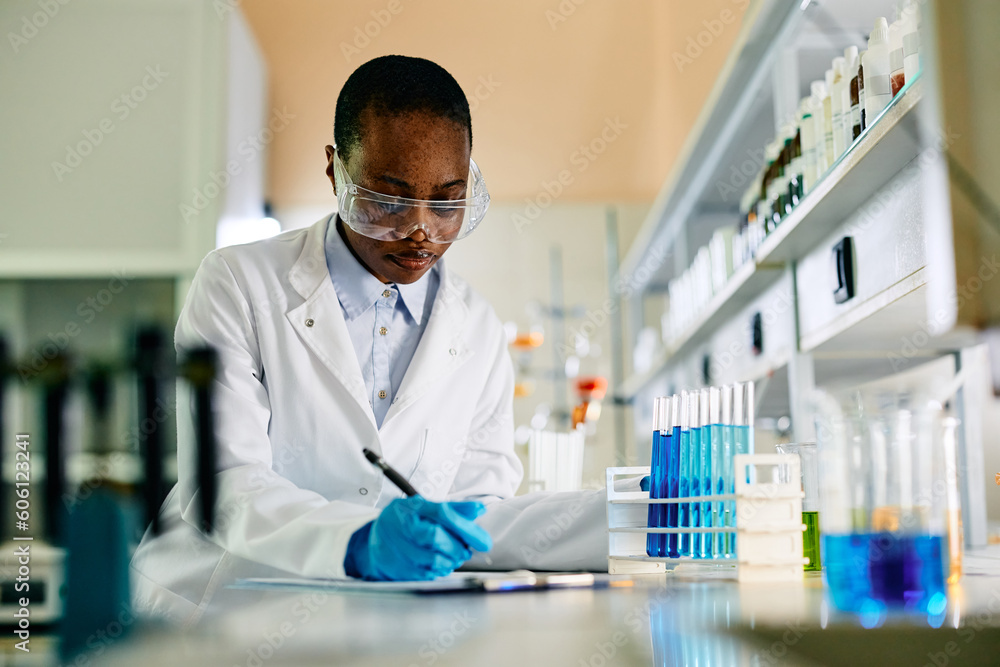 Black female scientist analyzing research data while working in laboratory. Black female scientist analyzing research data while working in laboratory.