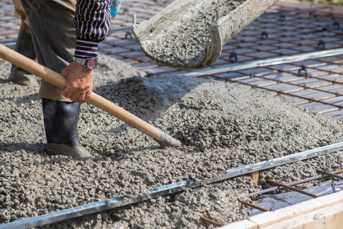 Worker picking up concrete with a shovel while.