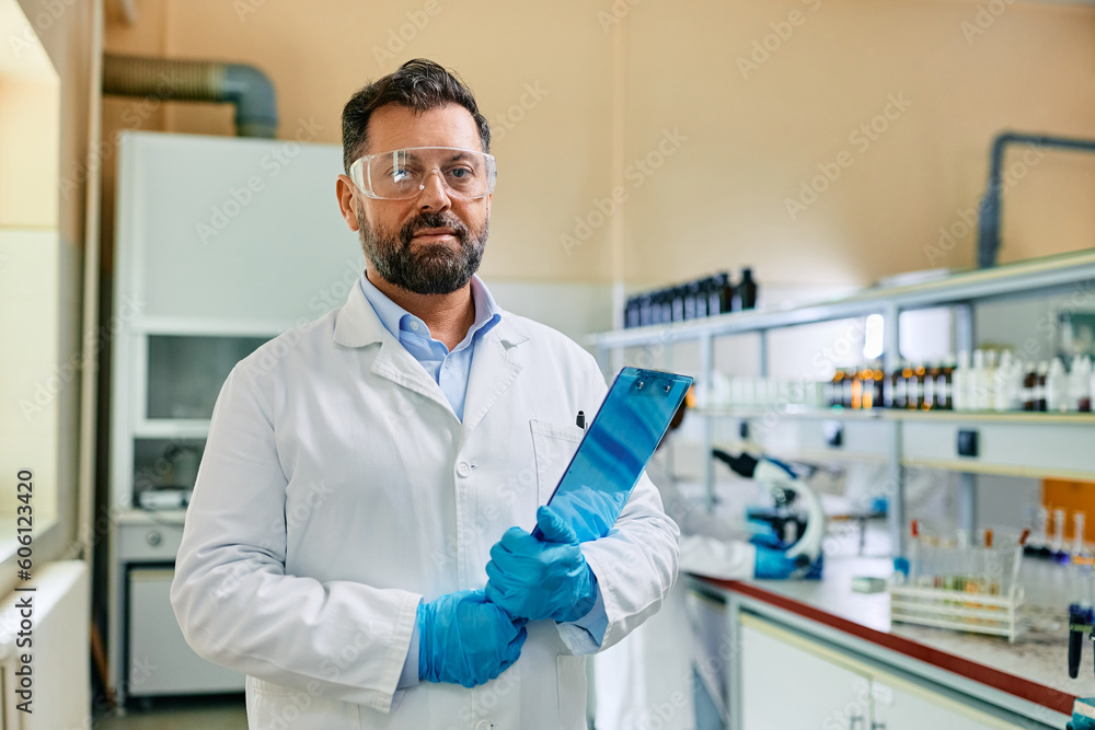 Male biochemist working in laboratory and looking at camera. Male biochemist working in laboratory and looking at camera.