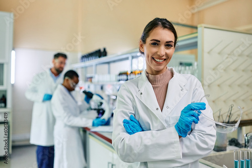 Young happy pharmaceutical scientist in laboratory looking at camera. © Drazen