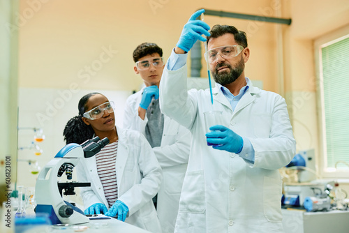 Pharmacy professor and his students working with test samples during scientific research in laboratory.