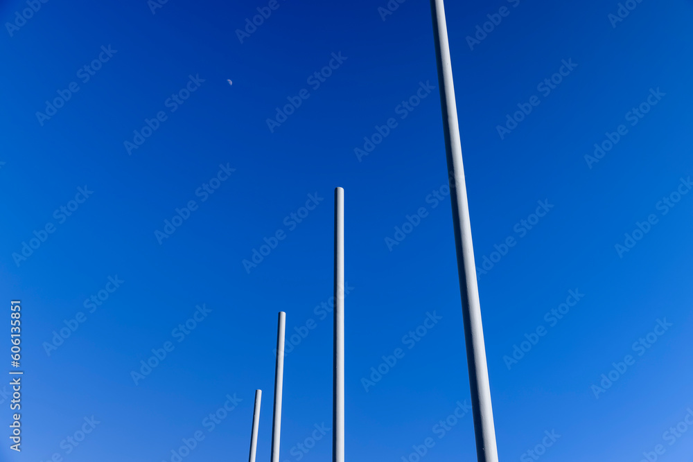a group of empty metal flagpoles against a blue sky background a group of empty metal flagpoles against a blue sky background
