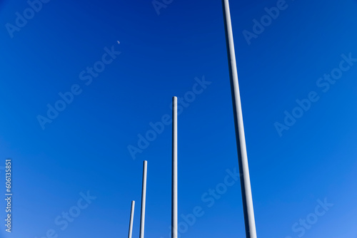 a group of empty metal flagpoles against a blue sky background photo