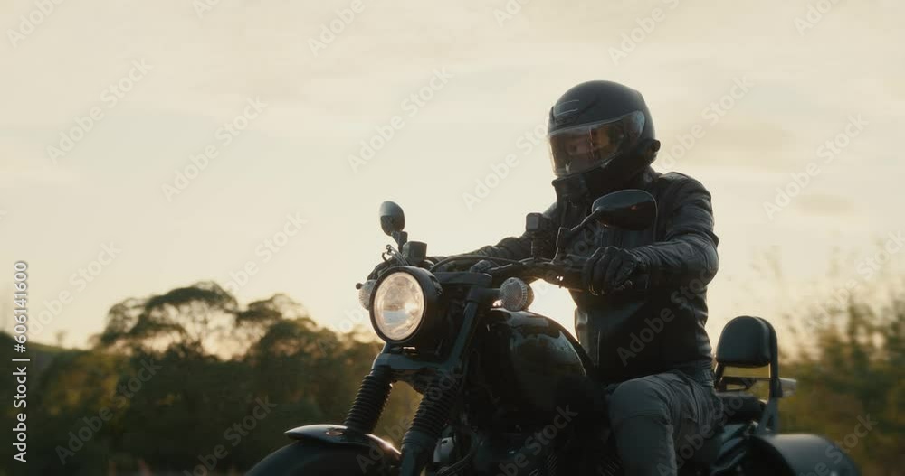 Man in a black leather jacket driving a black motorcycle through the dusk sky. Man in a black leather jacket driving a black motorcycle through the dusk sky.
