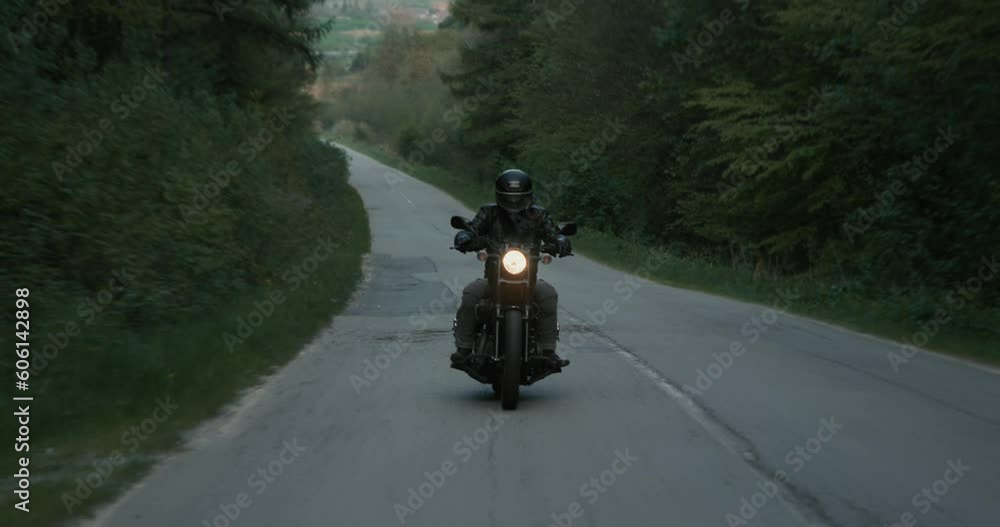 Tracking shot of a male biker driving on a country road in the evening. Tracking shot of a male biker driving on a country road in the evening.