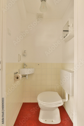 a small bathroom with a toilet and red rug on the floor in front of the toilet is an open door